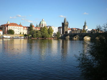Arch bridge over river by buildings against sky in city