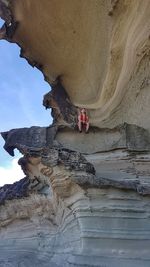 Low angle view of man on cliff against sky