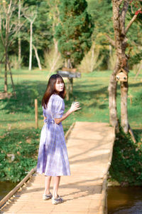 Young woman standing against trees