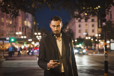 Portrait of young man standing on street at night