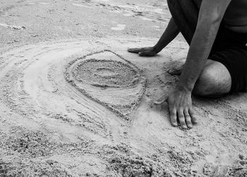 Low section of man by eye shape on sand at beach