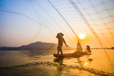 Man throwing fishing net in sea