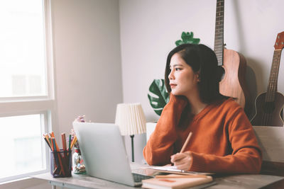 Young woman sitting on table at home