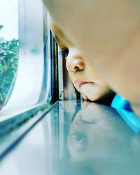 Close-up portrait of boy looking through window