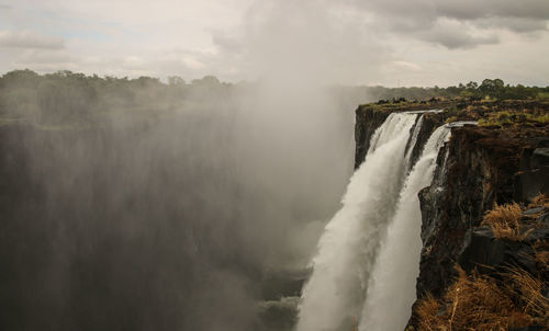 Scenic view of waterfall against sky