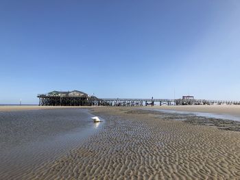 Surface level of beach against clear blue sky