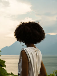 Rear view of afro woman looking at lake during sunset