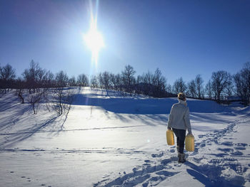 Rear view of woman on snow covered field against sky