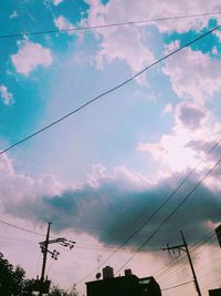 Low angle view of electricity pylon against cloudy sky