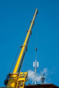 Low angle view of crane against blue sky