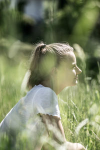 Woman sitting on field in sunny day