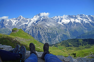 Low section of person on snowcapped mountains against sky