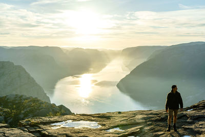 Rear view of man standing on mountain against sky