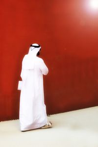 Rear view of man walking on floor against red wall