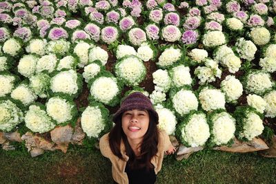 Portrait of young woman standing by purple cabbages growing on field