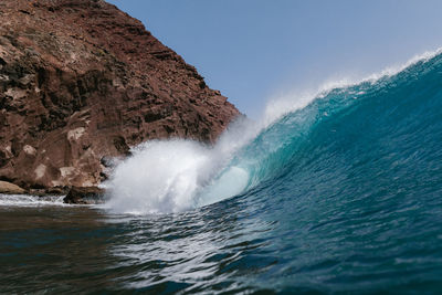 Blue wave breaking front a red mountain in tenerife