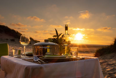 Drinks on table against sky during sunset