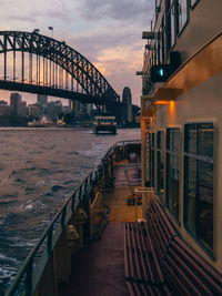 Bridge over illuminated city against sky at sunset