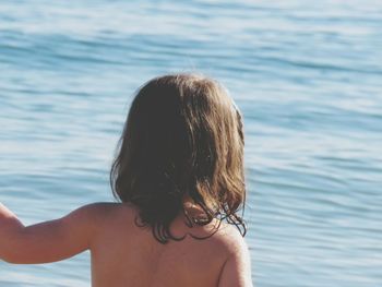 Rear view of topless girl against sea