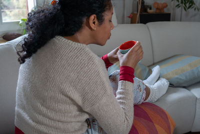 Midsection of woman sitting on sofa at home