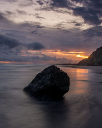 Rock formation in sea against sky during sunset