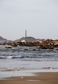 Lighthouse by sea against clear sky