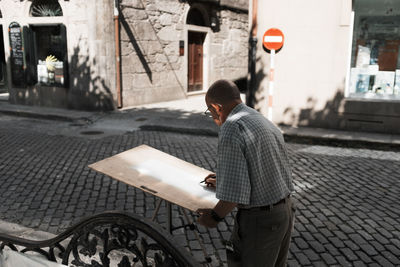 Side view of man walking on street against buildings