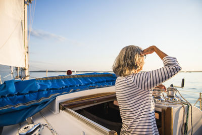 Rear view of man on boat sailing in sea against sky