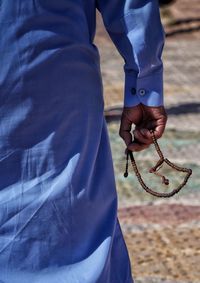 Midsection of man holding prayer beads in hands standing outdoors