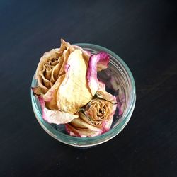 Directly above shot of wilted roses in drinking glass on table