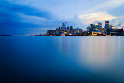 City at waterfront against cloudy sky