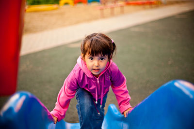 Portrait of cute girl playing on slide in playground