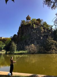 Man standing by lake against sky