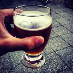 Close-up of hand holding beer glass on table