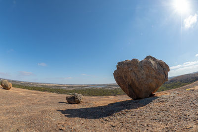 Rocks on land against sky on sunny day