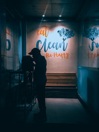 Rear view of man standing against illuminated wall