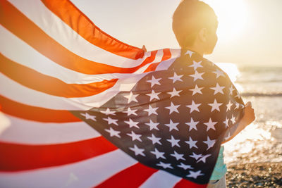 Boy holding american flag at beach