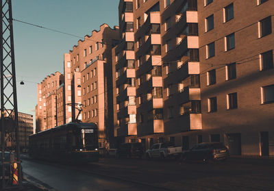 Cars on road by buildings against sky in city
