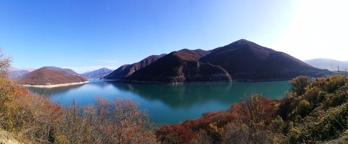 Scenic view of lake and mountains against clear blue sky