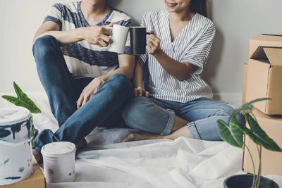 Midsection of woman using phone while sitting on sofa at home