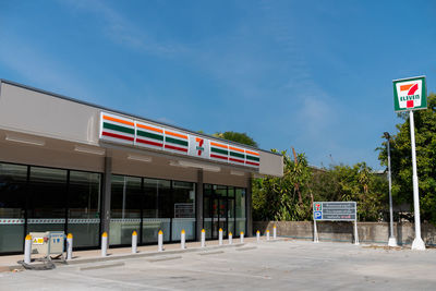 Empty road by building against blue sky