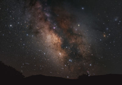 Low angle view of silhouette mountain against sky at night