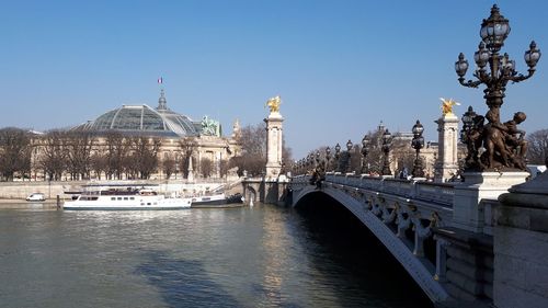 Statue and bridge in city against clear sky