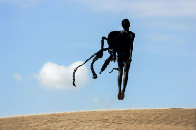 Teenage boy in costume levitating over desert against sky