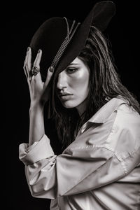 Portrait of young woman against black background