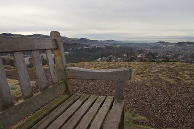 Empty bench on field against sky