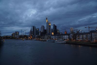 City at waterfront against cloudy sky