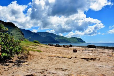 Ocean shore against cloudy sky