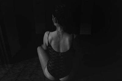 Rear view of woman sitting against black background