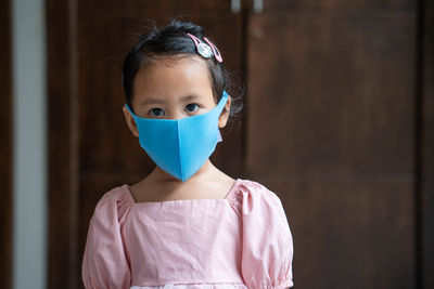 Cute little girl wearing healthy face mask to prevent virus and pm2.5 standing indoor.